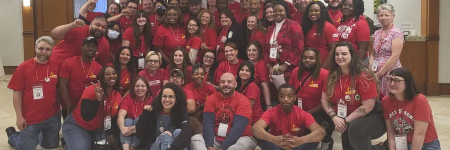 A group of Communication Workers of America sitting in matching red shirts for a group photo